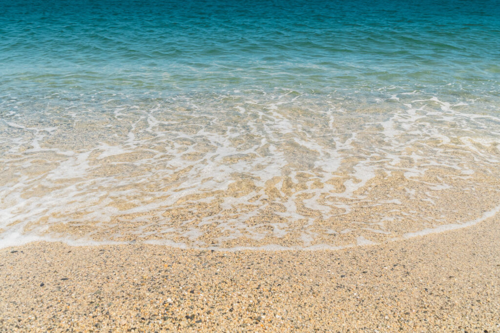 Summer beach sand blue waves and white foam