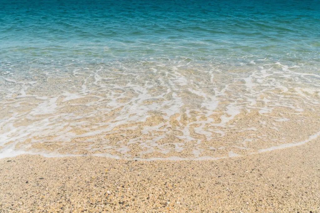 Summer beach sand blue waves and white foam